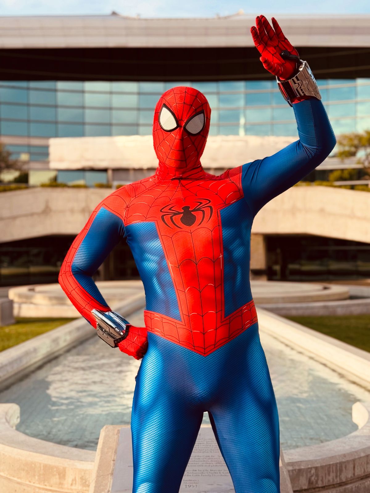 Spider hero character waving in front of a fountain